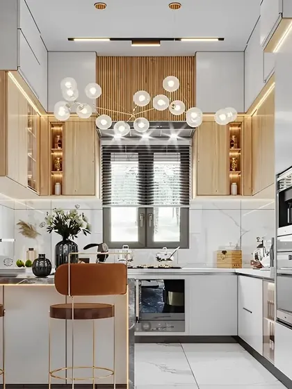 A glamorous kitchen design with a small island and statement chandelier. The combination of white marble, light wood, and gold accents creates a truly luxurious feel.