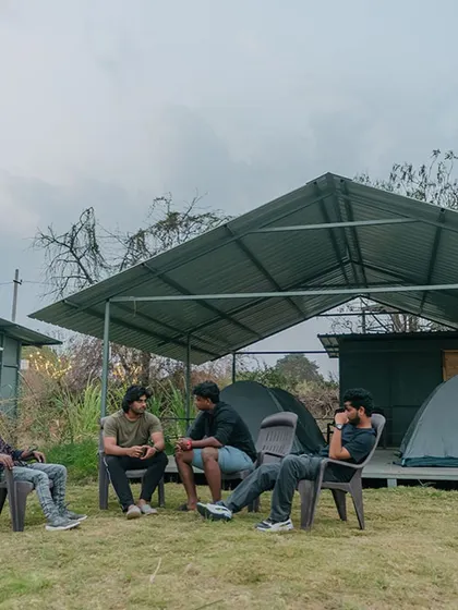 A group of colleagues relaxing and chatting outside their tents. Our covered tent platforms provide a comfortable, shaded area for your team to gather.