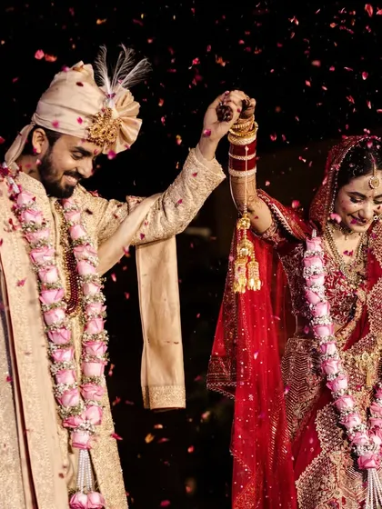 A moment of celebration after the varmala. The couple raises their hands as they are showered with petals, a perfect picture of joy and togetherness.