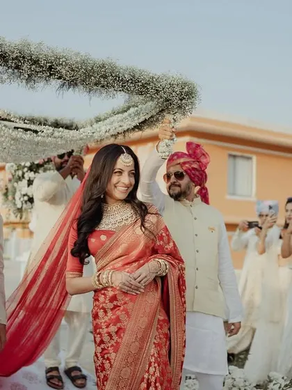 The smiling bride making her way to the mandap, surrounded by her loved ones.