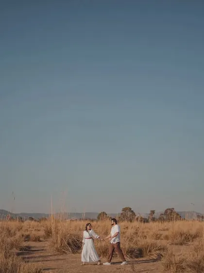 A beautiful wide-angle shot showing the couple in a vast, open landscape under a clear blue sky. This type of image is perfect for creating a sense of freedom and adventure.