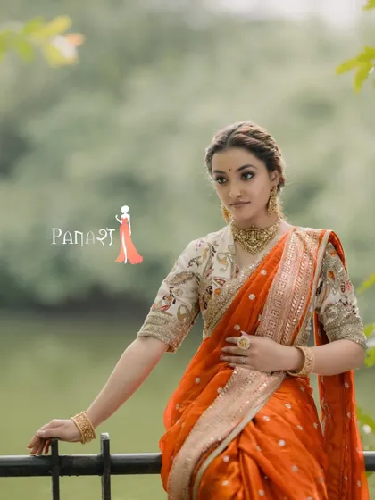 A full look of the vibrant orange Nauvari saree. The floral blouse adds a touch of modern femininity, making it a stunning choice for a bride or wedding guest who wants to stand out.