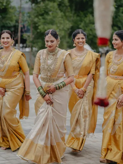 The bride with her bridesmaids, all coordinated in beautiful gold sarees, creating a picture of collective joy and elegance.