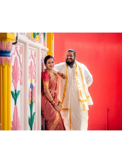 A relaxed portrait of a couple against a colorful, traditional backdrop.