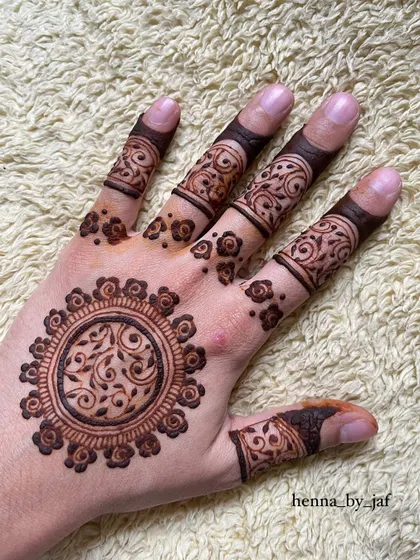 The same beautiful mandala design, but placed on the palm of the hand. The intricate details of the central vine pattern are clearly visible.
