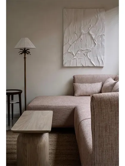 The guest bedroom features a comfortable L-shaped sofa and a textured white art piece, creating a serene and inviting atmosphere.