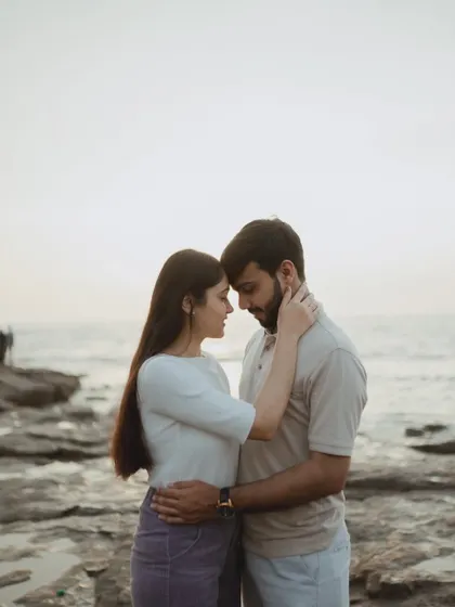 An intimate forehead-to-forehead pose on the rocky shores of Mumbai. This classic romantic shot captures the couple's deep connection with the sea as their witness.