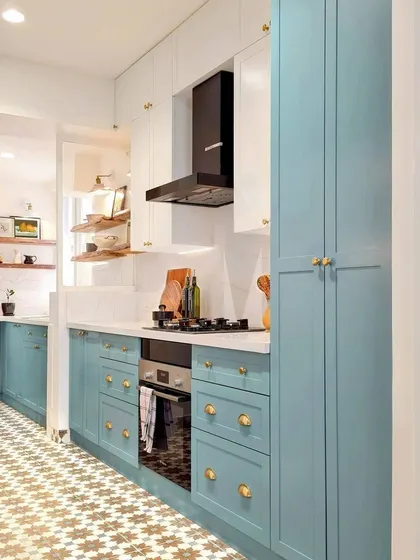 After: The transformation of the Breeze Home kitchen. By removing the door to the utility space and replacing the window, I created one long, cohesive room. The soft blue cabinetry, patterned floor tiles, and brass hardware give the space a fresh, custom feel.