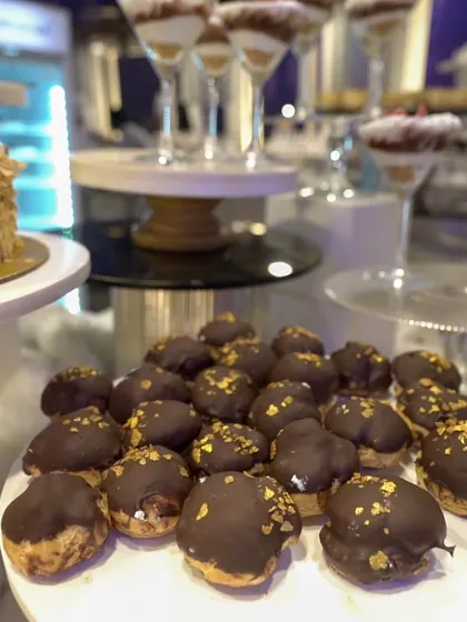 A close-up of our chocolate-dipped profiteroles, dusted with edible gold flakes. These elegant, bite-sized pastries are a luxurious addition to any dessert spread.