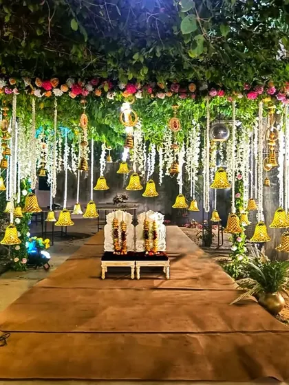 A breathtaking mandap setup under a canopy of natural greenery. I added hanging floral strings and dozens of brass bells to create a magical, temple-like feel for this nighttime wedding ceremony.
