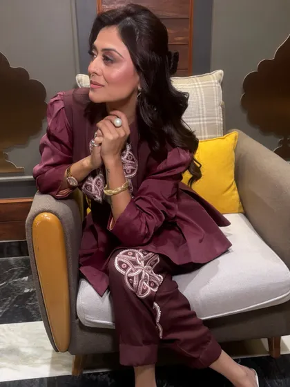 A lovely seated portrait of Falaq Naazz. Her soft, voluminous hairstyle perfectly complements her embroidered pantsuit, creating a chic and modern look.
