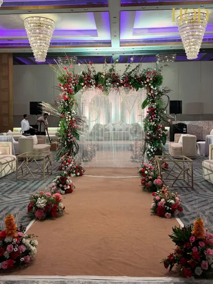 A wider perspective of the floral arch and aisle leading to the main seating area. The design creates a clear and beautiful pathway, guiding guests while enhancing the overall romantic theme of the event.