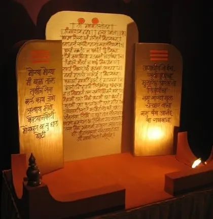 This image showcases a beautifully crafted Ganpati singhasan (throne) featuring panels with sacred Marathi verses. The soft, internal lighting highlights the script and creates a serene atmosphere for worship.