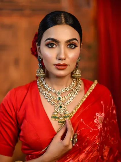 A powerful close-up portrait in a classic red blouse. The focus is on the model's confident expression and the stunning statement necklace.