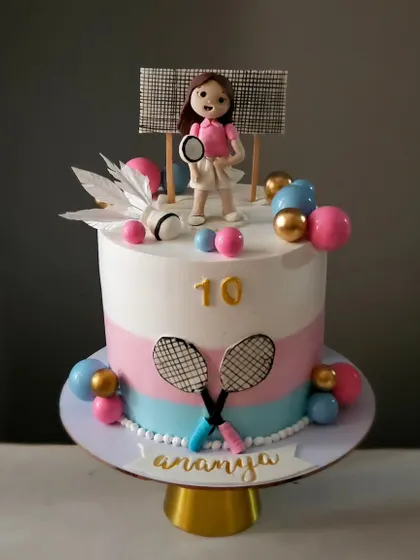 This badminton-themed cake was created for a 10th birthday. It features a personalized figurine of the birthday girl, along with edible rackets and a shuttlecock made from delicate wafer paper.