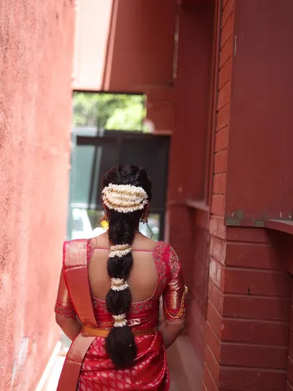 A view of the bride's intricate hairstyle from the back. The braid is adorned with fresh flowers, a classic element of South Indian bridal beauty.
