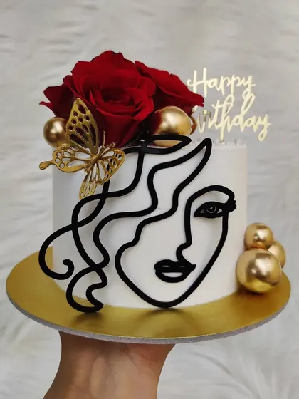 This line art cake uses a black topper for a bold contrast against the white buttercream. The fresh red roses add a touch of classic romance.