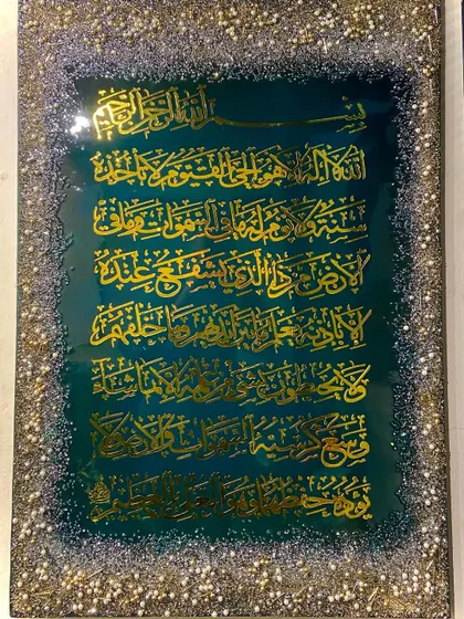 This Ayat al-Kursi piece features a deep green background and a full, glittering border, creating a jewel-like effect.