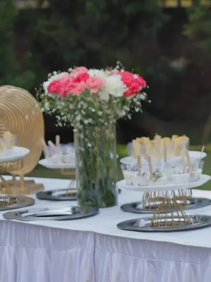 An outdoor setup for a beautiful baby shower. The table is adorned with fresh flowers and a variety of treats, creating a joyful and celebratory scene.