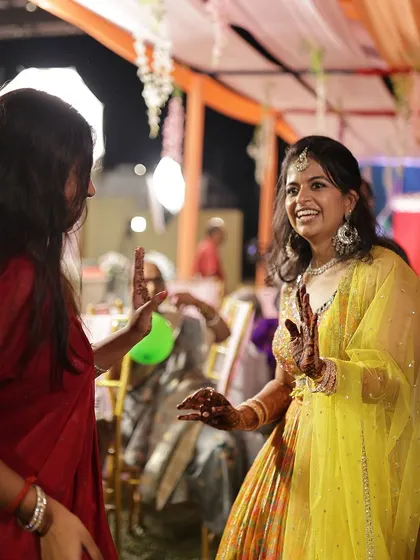The bride enjoying a dance with a friend, her hands and mehendi in motion.