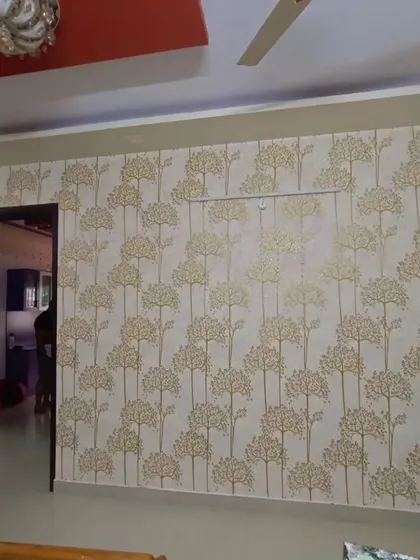 A living room wall with a simple tree pattern wallpaper. The design is clean and modern, adding a subtle natural element to the space.