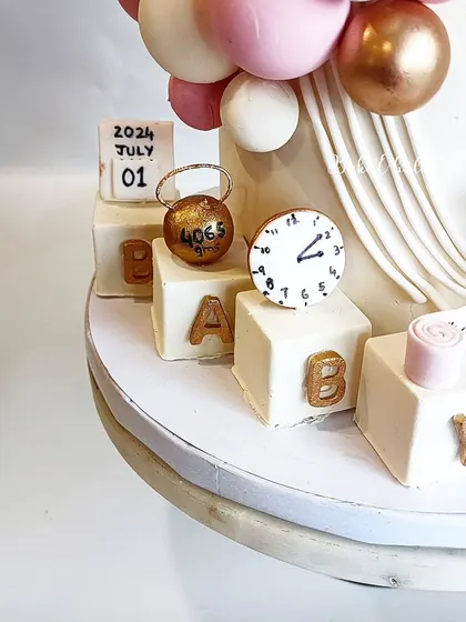 A close-up of the birth announcement details. The spheres and cubes are all made of delicious chocolate, making the entire cake a treat.