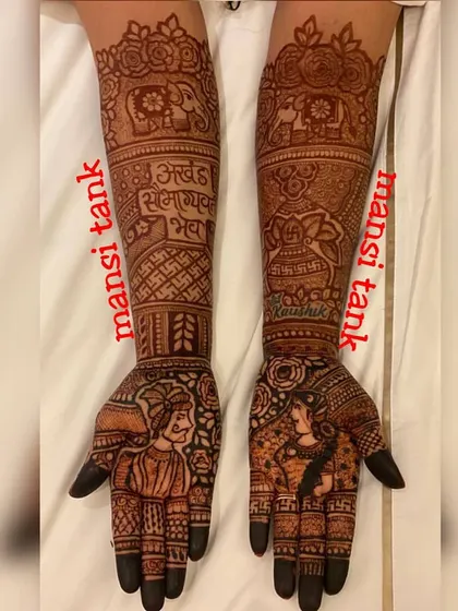 A classic bridal design featuring portraits of the groom and bride on the palms. The arms are decorated with elephants and a Sanskrit blessing, "Akhand Saubhagyavati Bhava," wishing the bride eternal marital bliss.