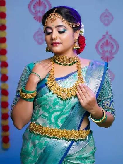 A close-up on the bride's makeup and jewelry. The lighting is carefully placed to make the gold shine and highlight the flawless makeup application.