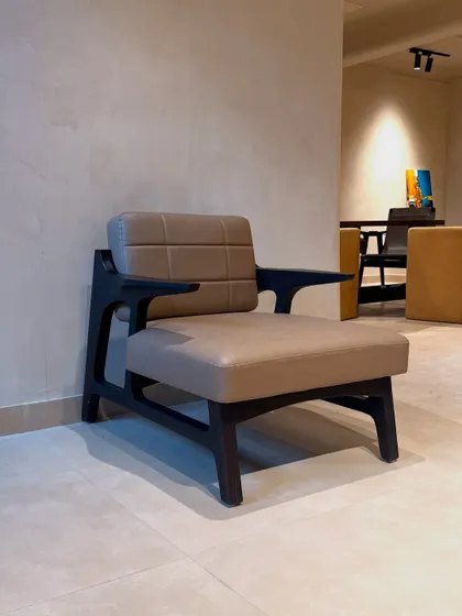 This sharp and sexy armchair features a dark wood frame treated with the Shou-Sugi-Ban technique and chocolate-colored leatherette upholstery. The stitch detailing adds a classic touch, making it perfect for a home office.