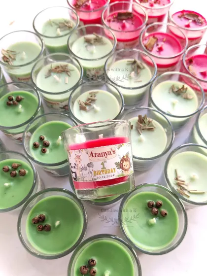Votive jar candles in green and red, topped with spices and botanicals, for Aranya's jungle-themed first birthday party.