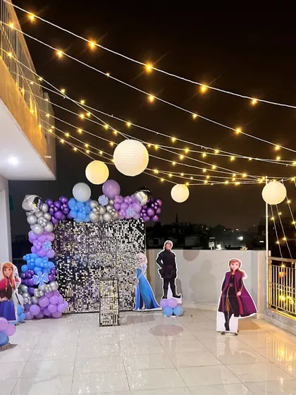 The entire Frozen setup at night, with the sequin wall shimmering under the glow of fairy lights and paper lanterns.
