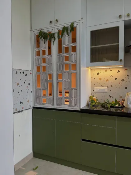 Final form: cottage-core meets ‘I have Pinterest boards for every life decision.’ A custom pooja unit with intricate jali work, integrated seamlessly into this green and terrazzo kitchen.