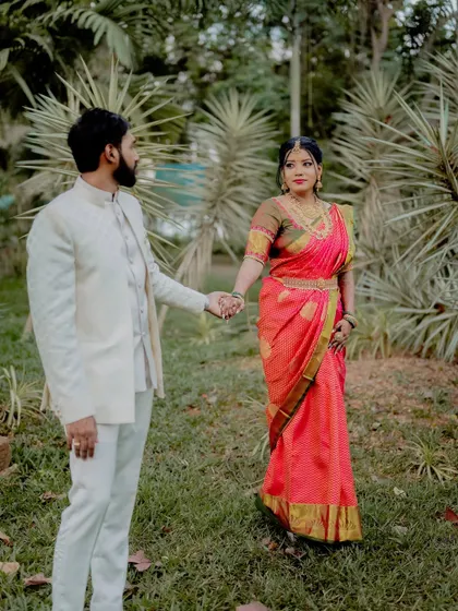 A classic wedding portrait pose. The couple holds hands, standing together in a beautiful garden setting, creating a timeless image of their union.