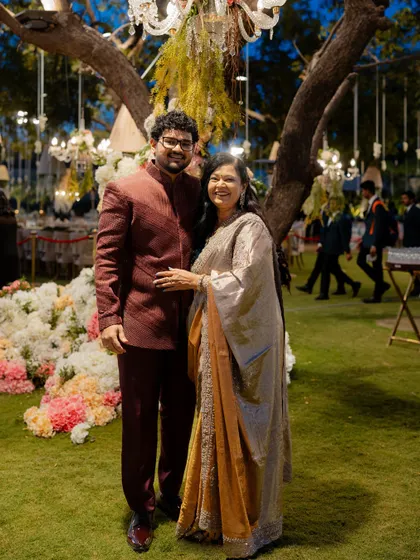 The groom with his mother, both styled in complementary outfits that reflect their personal tastes while fitting the event's aesthetic.