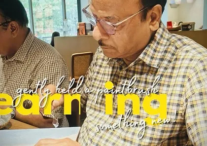 A close-up of a father learning something new, gently holding a paintbrush for the first time.