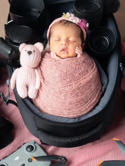 This little photographer is sleeping soundly in a camera bag, surrounded by lenses and drones.