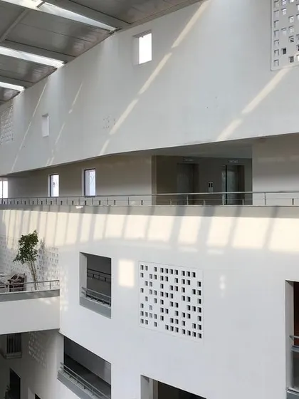The interplay of light and shadow across the atrium walls, created by the large skylight above. This ever-changing pattern brings the building to life throughout the day.