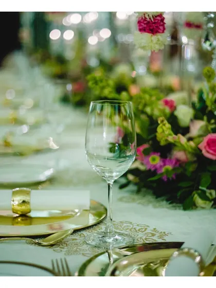 A macro shot focusing on the fine details of our tablescapes, from the polished wine glass to the golden napkin ring and intricate plate design.