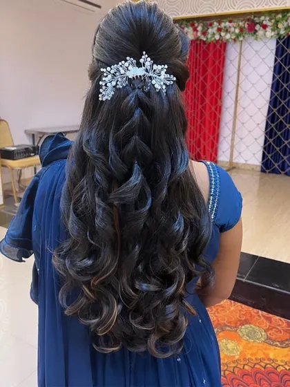 A beautiful engagement hairdo that combines a central braid with soft, flowing curls. A crystal hairpiece placed at the top of the braid adds a touch of sparkle.