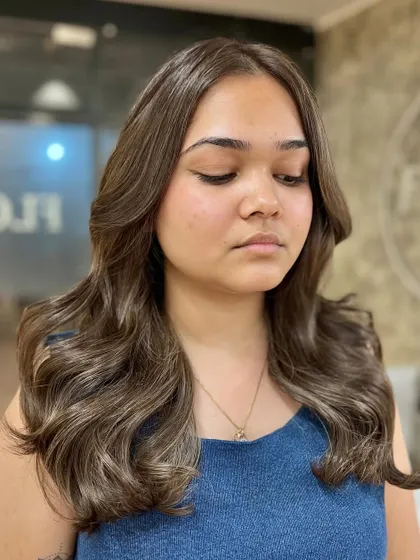 This client is glowing with her new ash brown color. The shade complements her skin tone perfectly, and the soft waves give it a stylish finish.