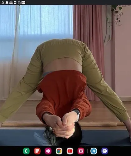 An online one on one session, guiding a student in Prasarita Padottanasana (Wide-Legged Forward Bend). Virtual classes allow for personalized feedback on posture and alignment, no matter where you are.