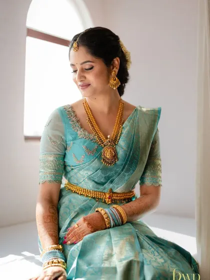 A beautiful, sun-kissed shot of the bride by the window. The natural light highlights the flawless, glowing finish of her makeup.