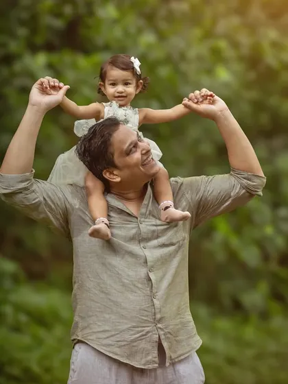 A father gives his smiling daughter a shoulder ride as they explore a park together. This shot captures a classic, fun-filled father-daughter moment, full of trust and happiness.