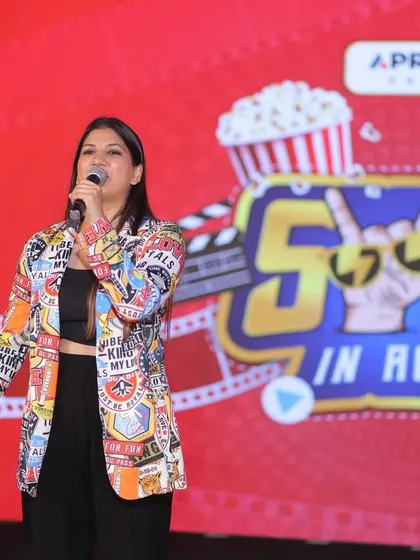 Taking the stage at the Apraava 'Swag in Action' event. The vibrant, movie-themed backdrop set the tone for a night of fun and celebration.