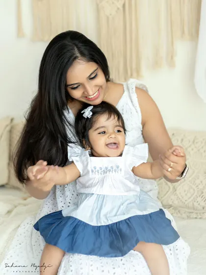 A duplicate of image 19, a mother and her happy baby girl. Their bright smiles and the simple background make for a classic and joyful portrait.