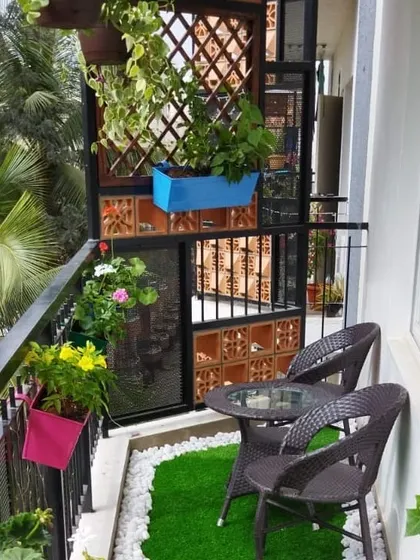 The other side of the same balcony, featuring a cozy seating area, a trellis with climbers, and railing planters, creating a private and functional outdoor room.