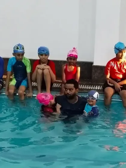 The full group of summer camp participants with their coach in the pool.