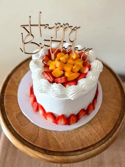 Celebrating summer with this fresh fruit cake. It's a light vanilla cake filled with layers of fresh cream and fruit, topped with mangoes and strawberries and decorated with sliced strawberries around the base.