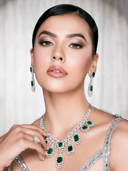 A striking beauty close-up. The flawless makeup, polished hair, and magnificent emerald jewelry create a look of sophisticated glamour.