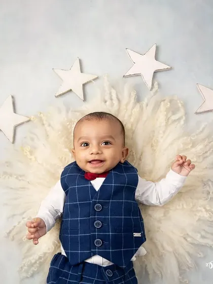 A little star on cloud nine. This infant portrait uses a soft, fluffy rug and wooden stars to create a dreamy, celestial-themed setup for a baby boy.